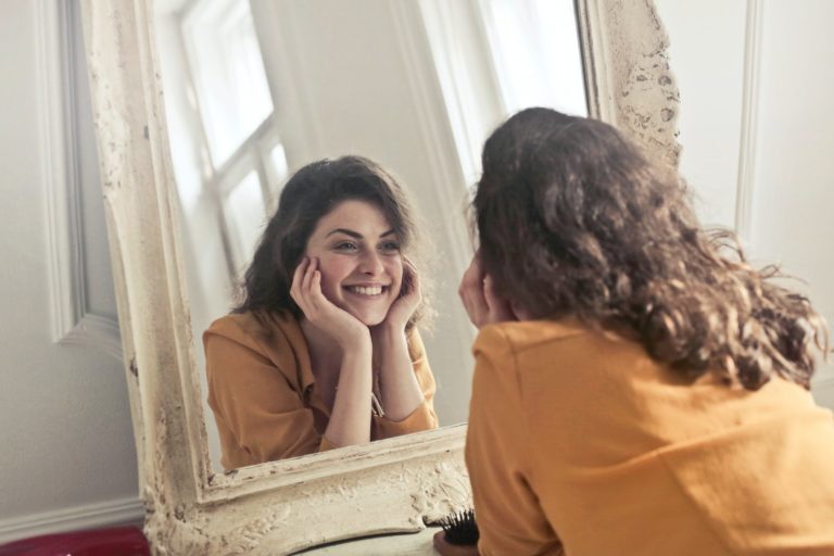 femme visage regarder miroir rides limiter apparition gestes sourire