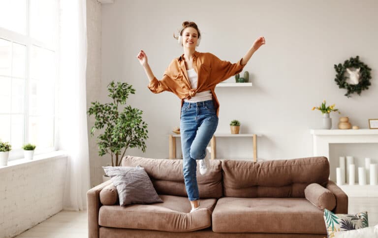femme joie sourire sauter canapé salon appartement déco lumineux