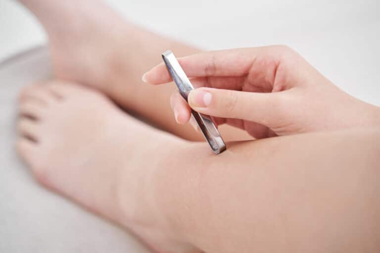 femme pince à épiler épilation poils incarnés jambes main