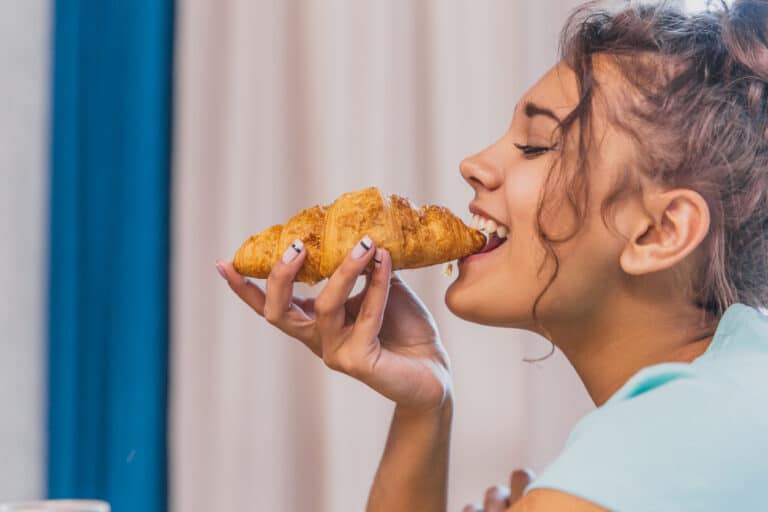 femme manger croissant goûter aliment repas viennoiserie gourmande