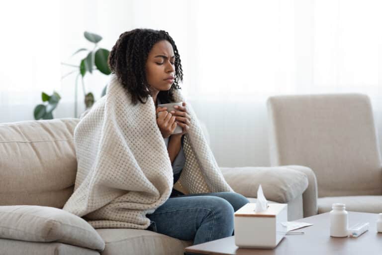 femme malade rhume virus hiver froid plaid canapé mouchoirs se moucher