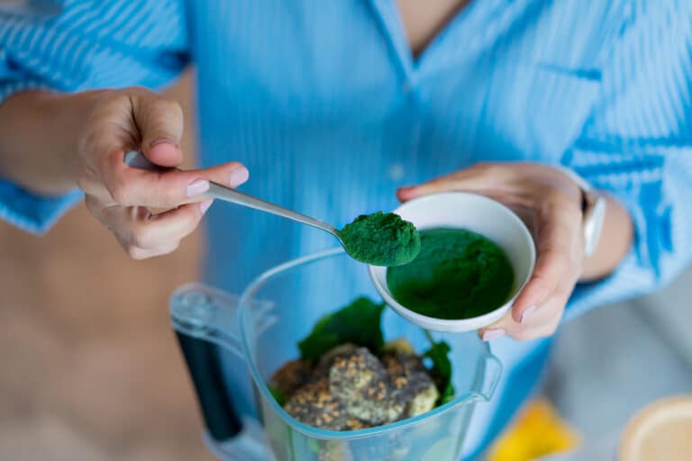 femme verser spiruline poudre verte algue blender smoothie jus de fruits